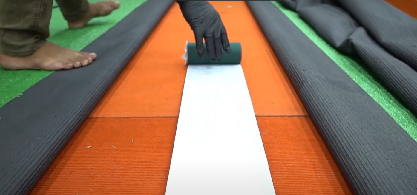 A worker using joint tape and turf glue method as artificial grass installation to bind them together.