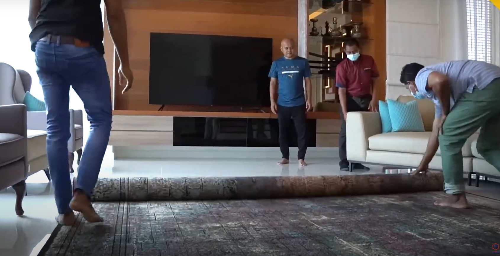 Group of workers rolling out a dark patterned carpet in a contemporary living room