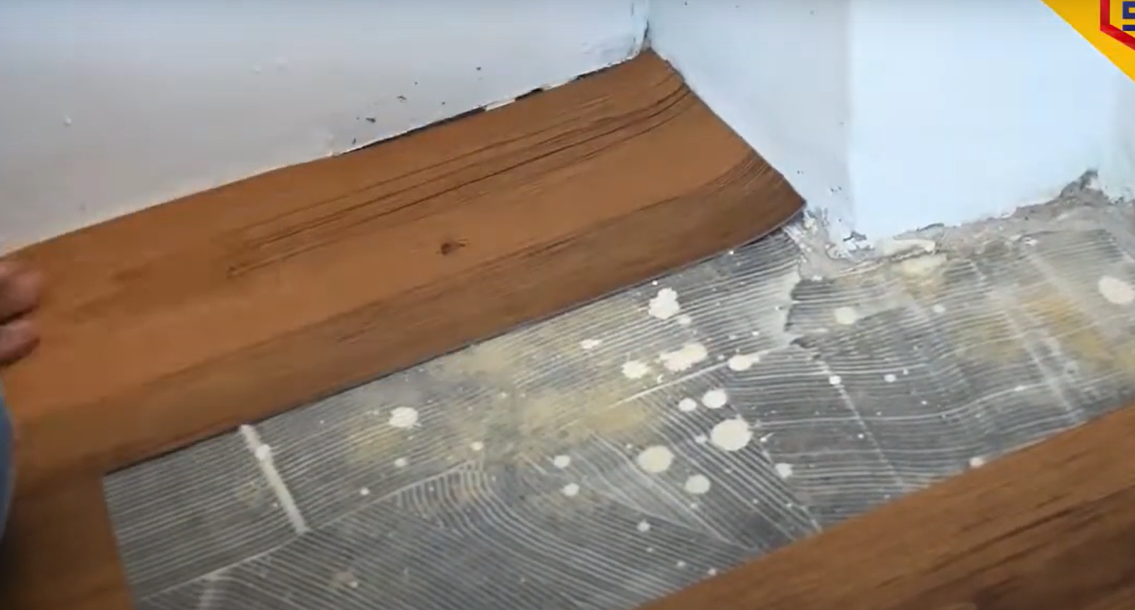 A worker showing the step of vinyl flooring installation process on the floor